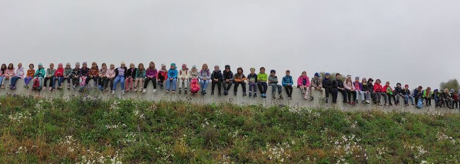 Alle Schulkinder sitzen nebeneinander auf einer Mauer