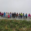 Alle Schulkinder sitzen nebeneinander auf einer Mauer