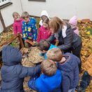 Schulkinder befüllen ein Igelgehege mit Stroh